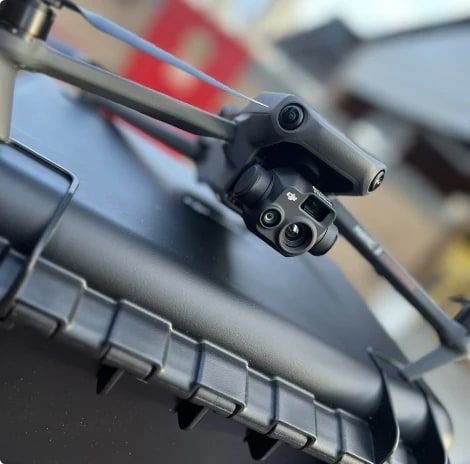 Drone com câmera térmica e câmera de zoom sob o corpo, pousado sobre a maleta de transporte