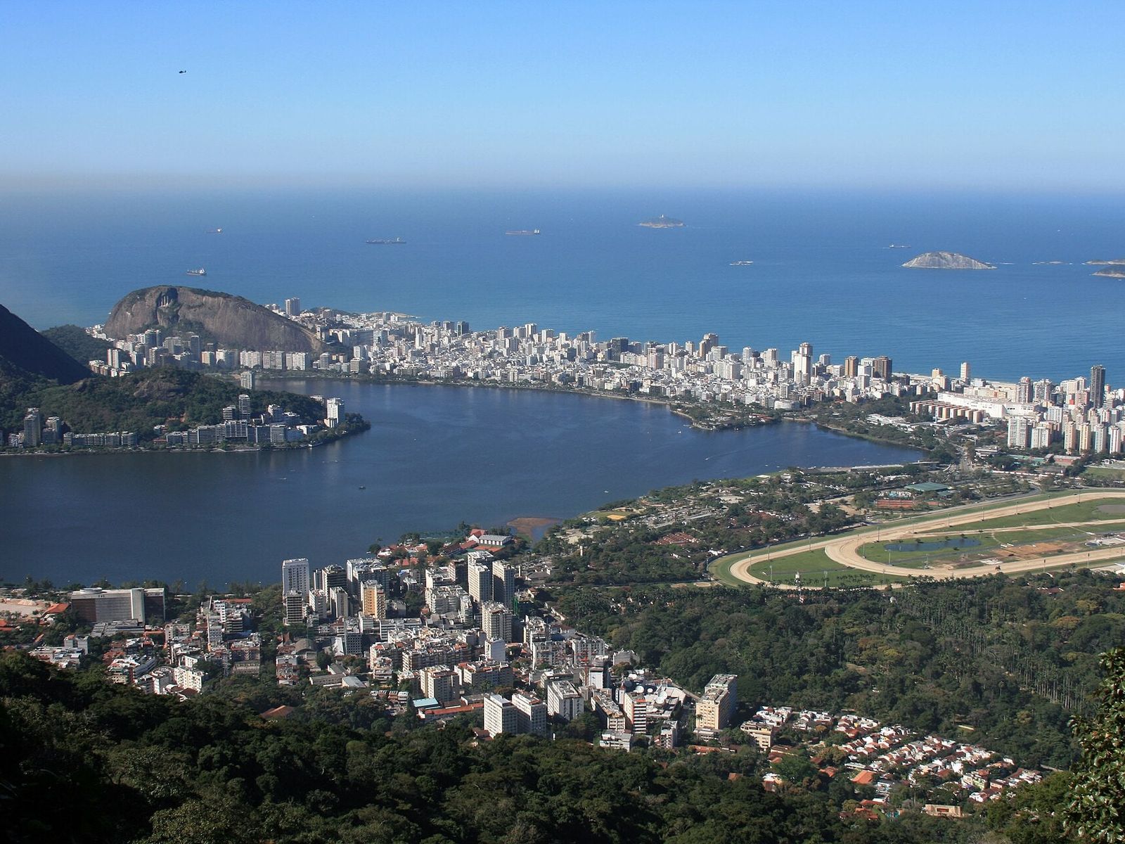 Lagoa Rodrigo de Freitas vista do alto, entre a mata e os bairros, com o mar e as ilhas ao fundo